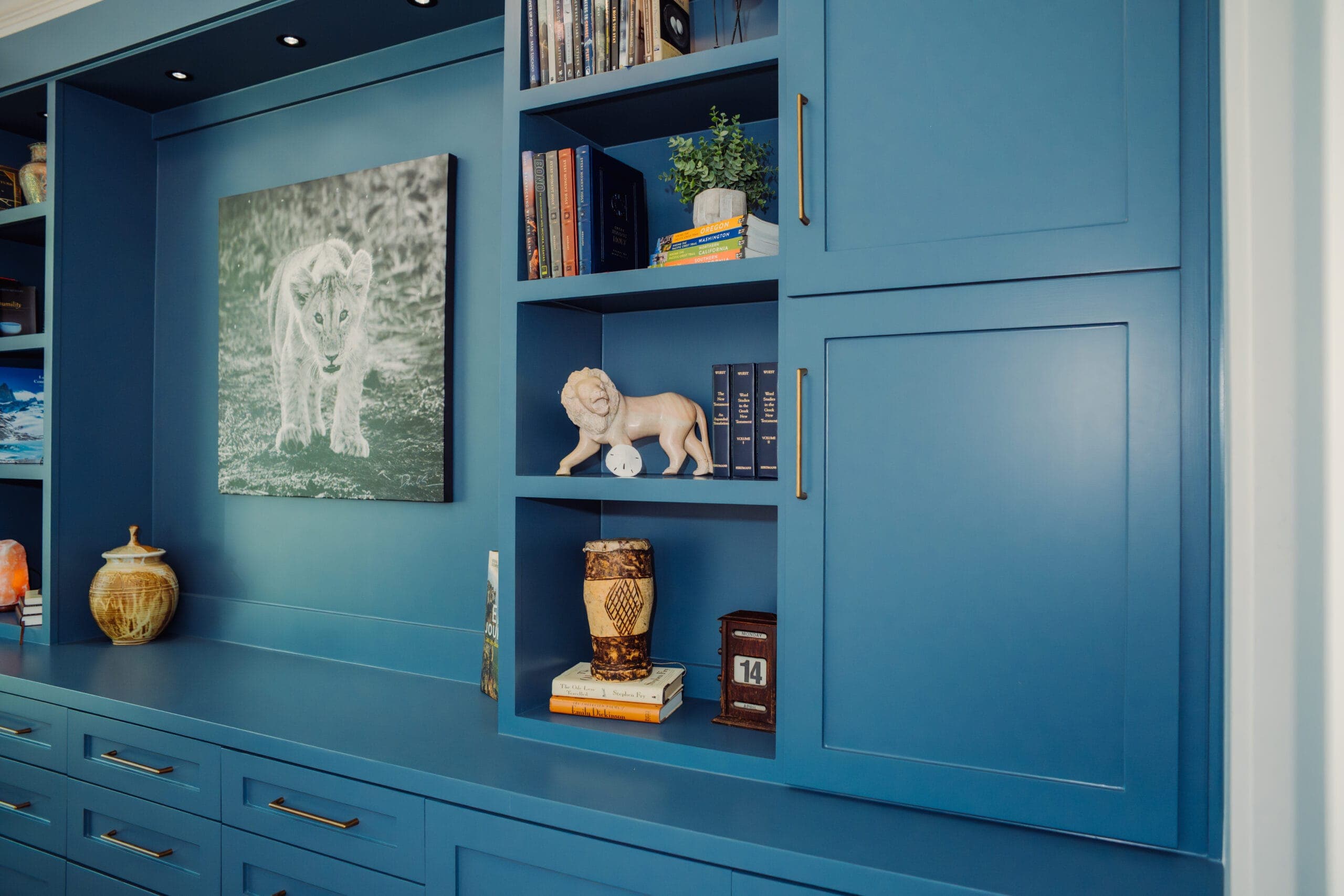 Blue painted built-in bookcase wall with open shelving and closed base cabinets