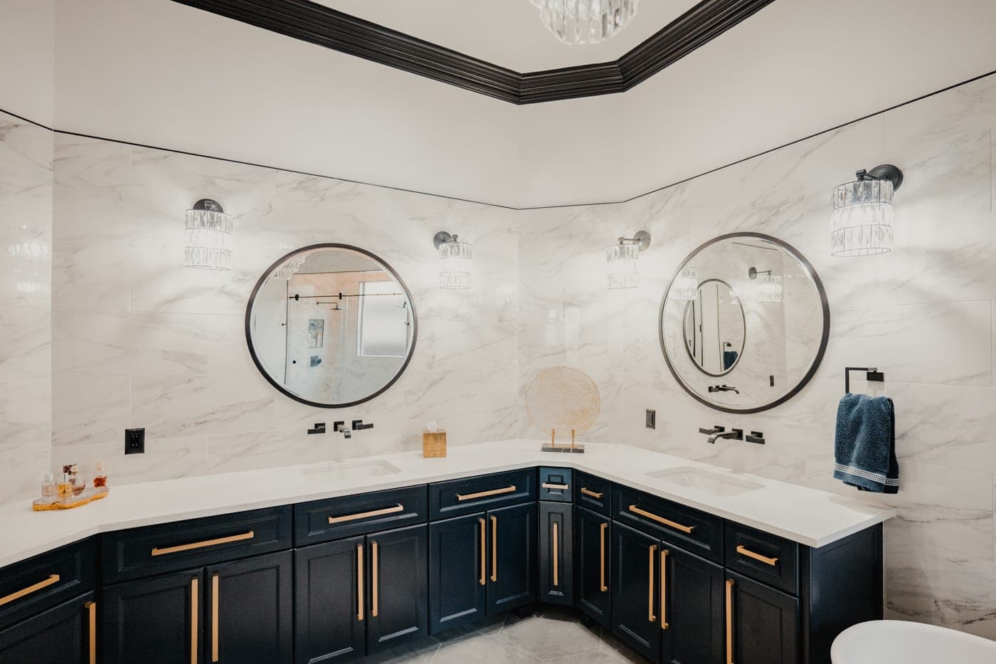 Navy shaker vanity with brass pulls against full-height marble-look wall tile