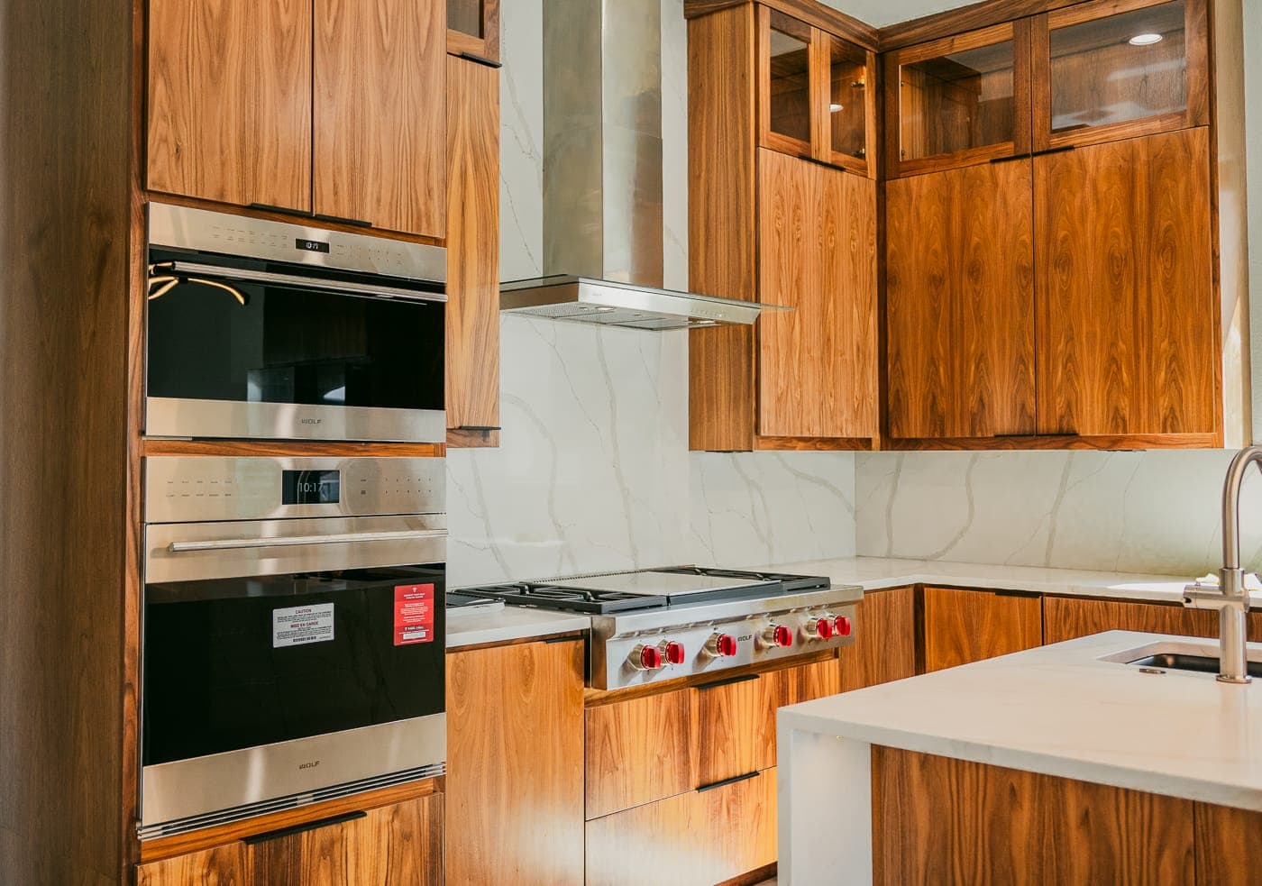 Walnut kitchen cabinetry with stainless wall ovens and a gas range — whole-home remodeling by Southlake Luxury Kitchens, serving Southlake, TX